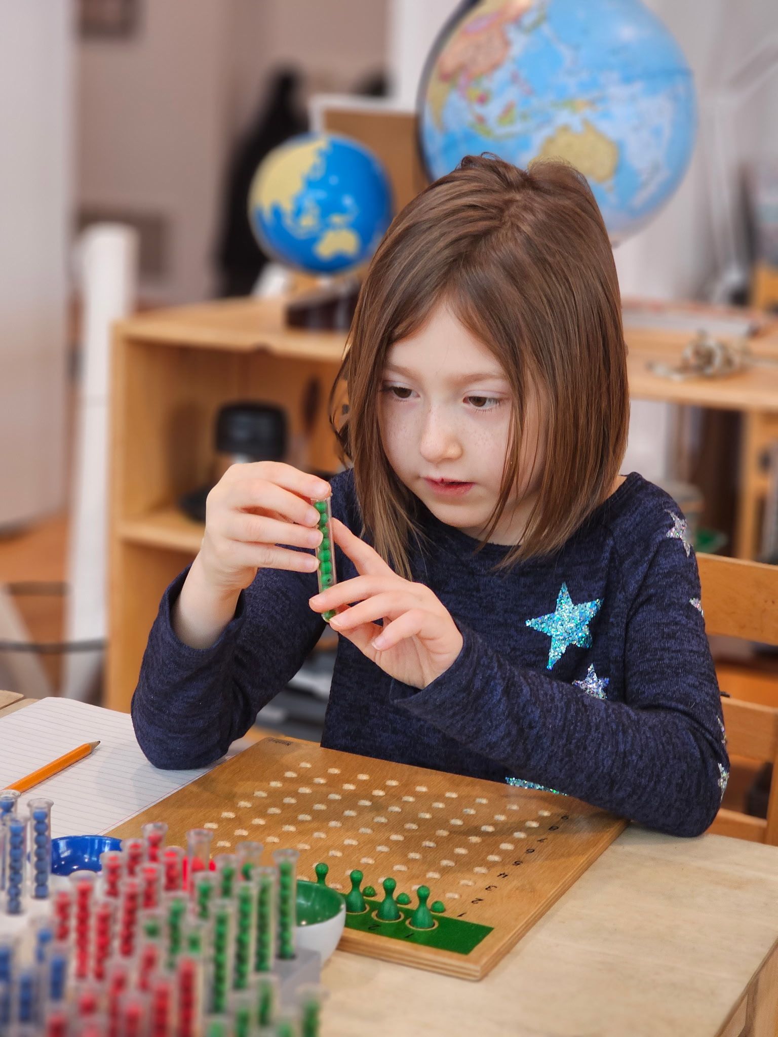 Child using Montessori racks and tubes to explore long division hands-on.