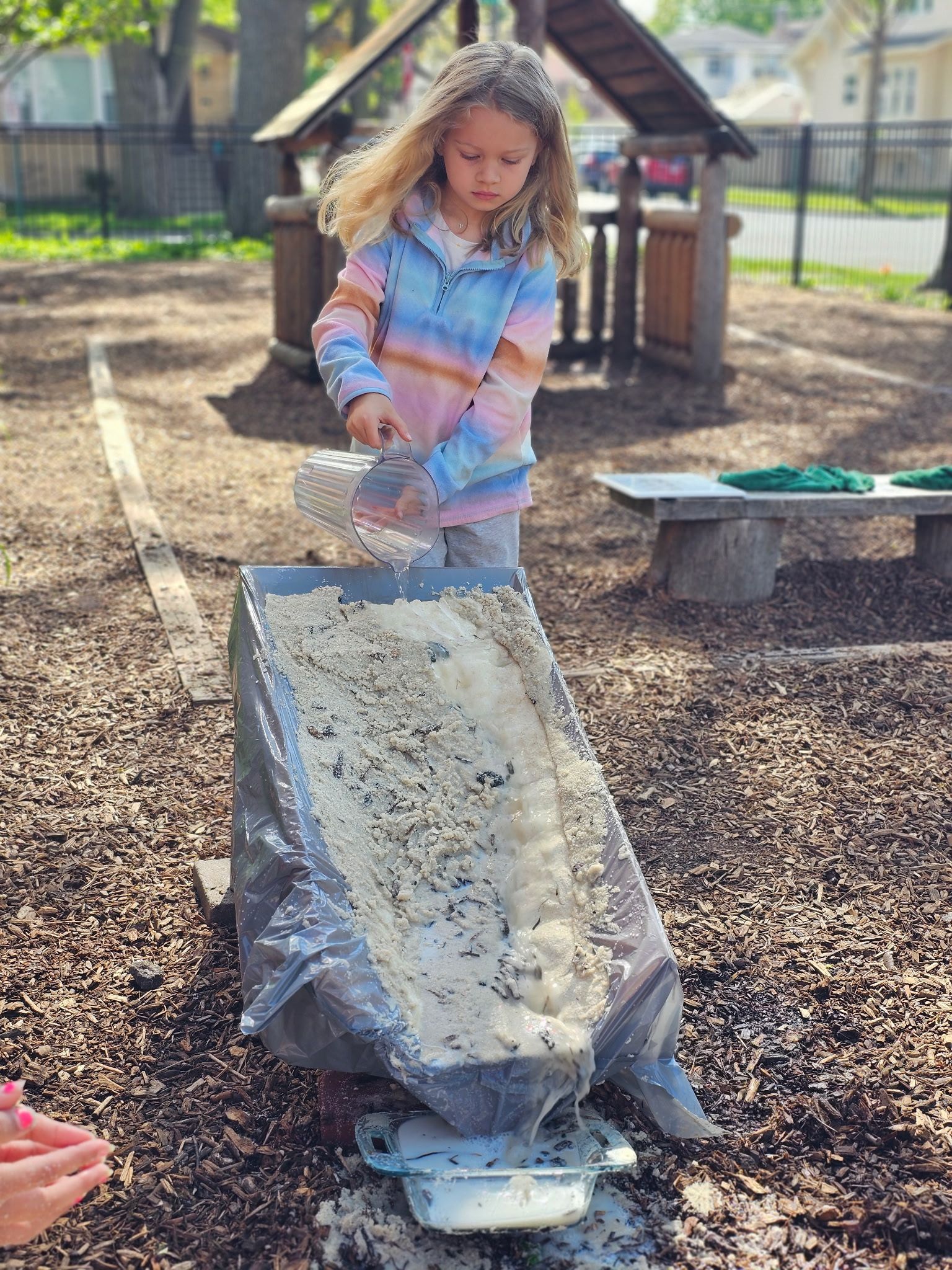 Child on a playground pouring water down a handmade waterfall.