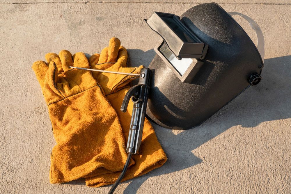 A Welding Helmet, Gloves, and Welding Torch Are on The Ground — Alice Hosetech & Industrial Supplies in Ciccone, NT
