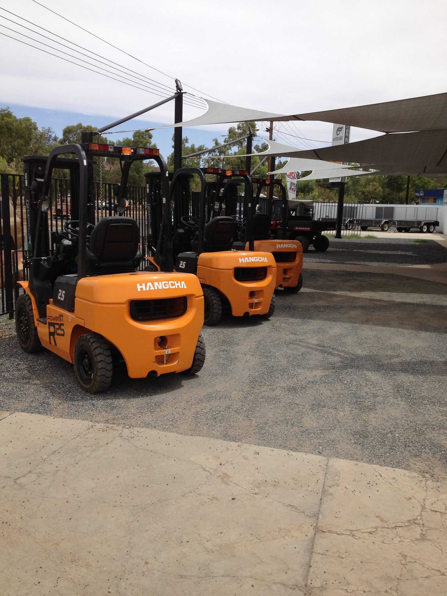 A Row of Orange Forklifts Are Parked in A Gravel Lot — Alice Hosetech & Industrial Supplies in Ciccone, NT