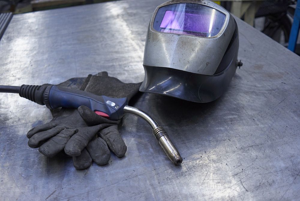 A Welding Helmet and Gloves Are on A Metal Table — Alice Hosetech & Industrial Supplies in Ciccone, NT