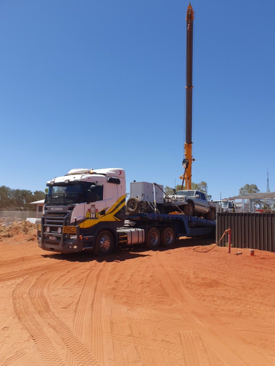 A Yellow Tractor Is Being Towed by A Tow Truck — Alice Hosetech & Industrial Supplies in Ciccone, NT