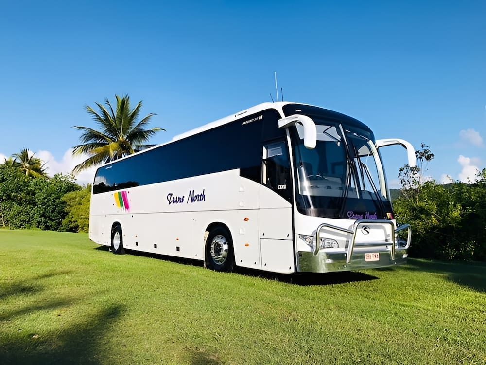A White Bus Is Parked In A Grassy Field — CC Couriers FNQ in Portsmith, QLD