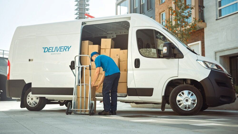 A Delivery Man Is Loading Boxes Into A Delivery Van — CC Couriers FNQ in Portsmith, QLD