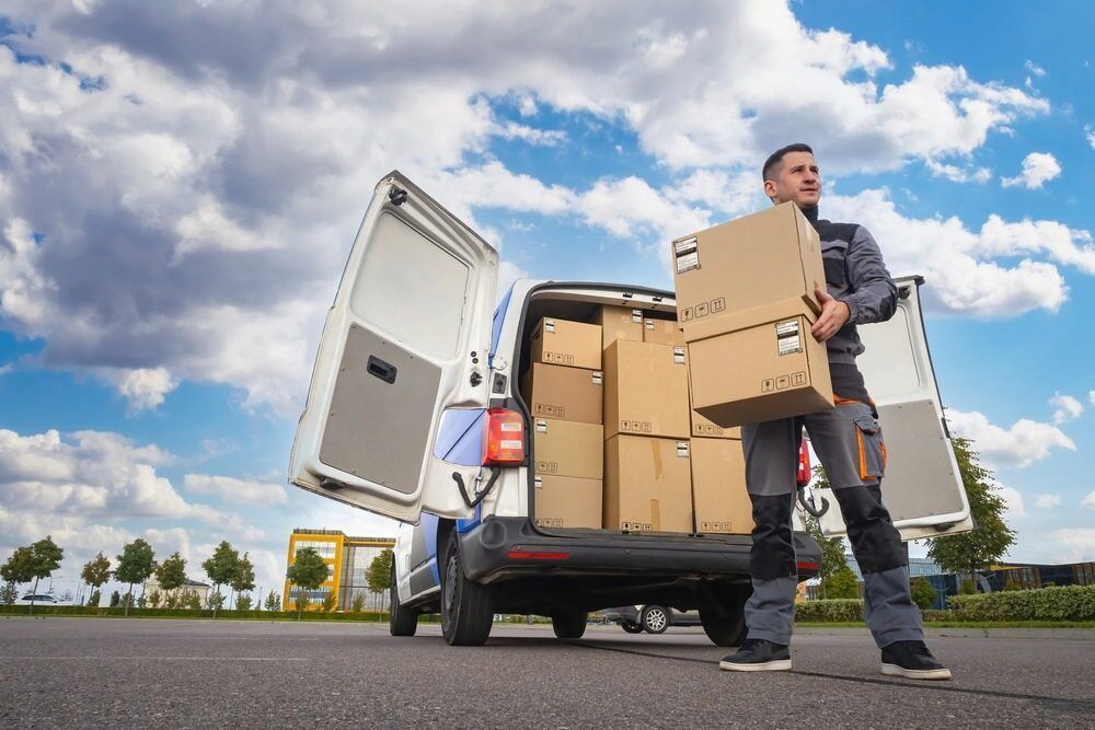 A Delivery Man Is Standing In Front Of A Van Filled With Boxes — CC Couriers FNQ in Portsmith, QLD