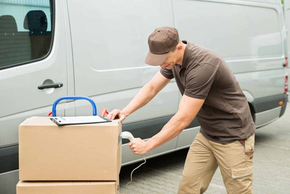 A Delivery Man Is Packing Boxes In Front Of A Van — CC Couriers FNQ in Port Douglas, QLD