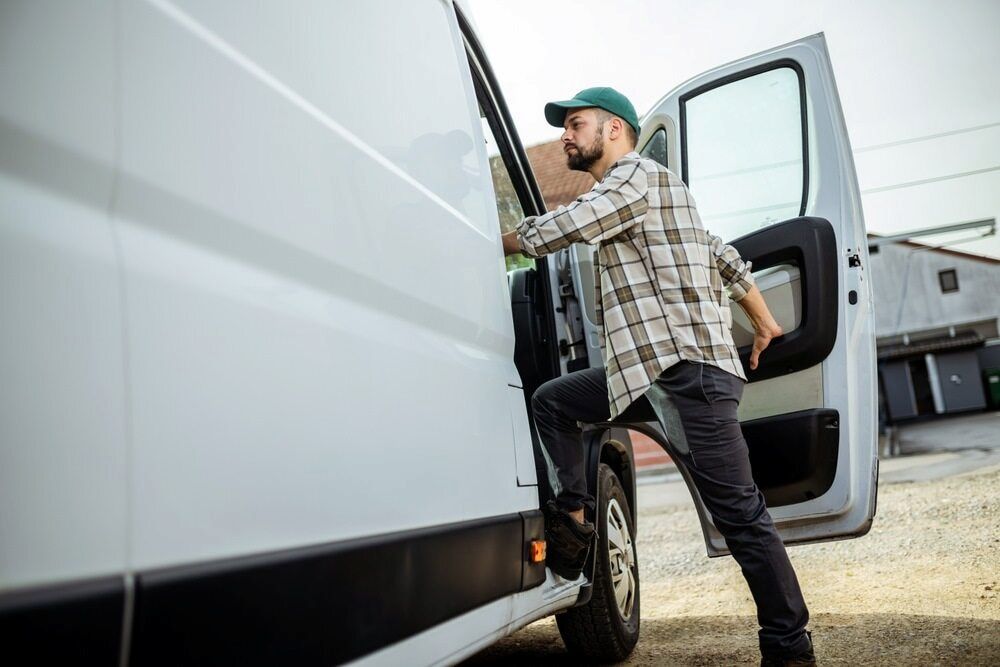 A Delivery Man Is Loading A Box Into A White Van — CC Couriers FNQ in Portsmith, QLD