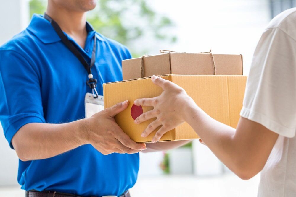 A Delivery Man Is Handing A Box To A Woman — CC Couriers FNQ in Portsmith, QLD