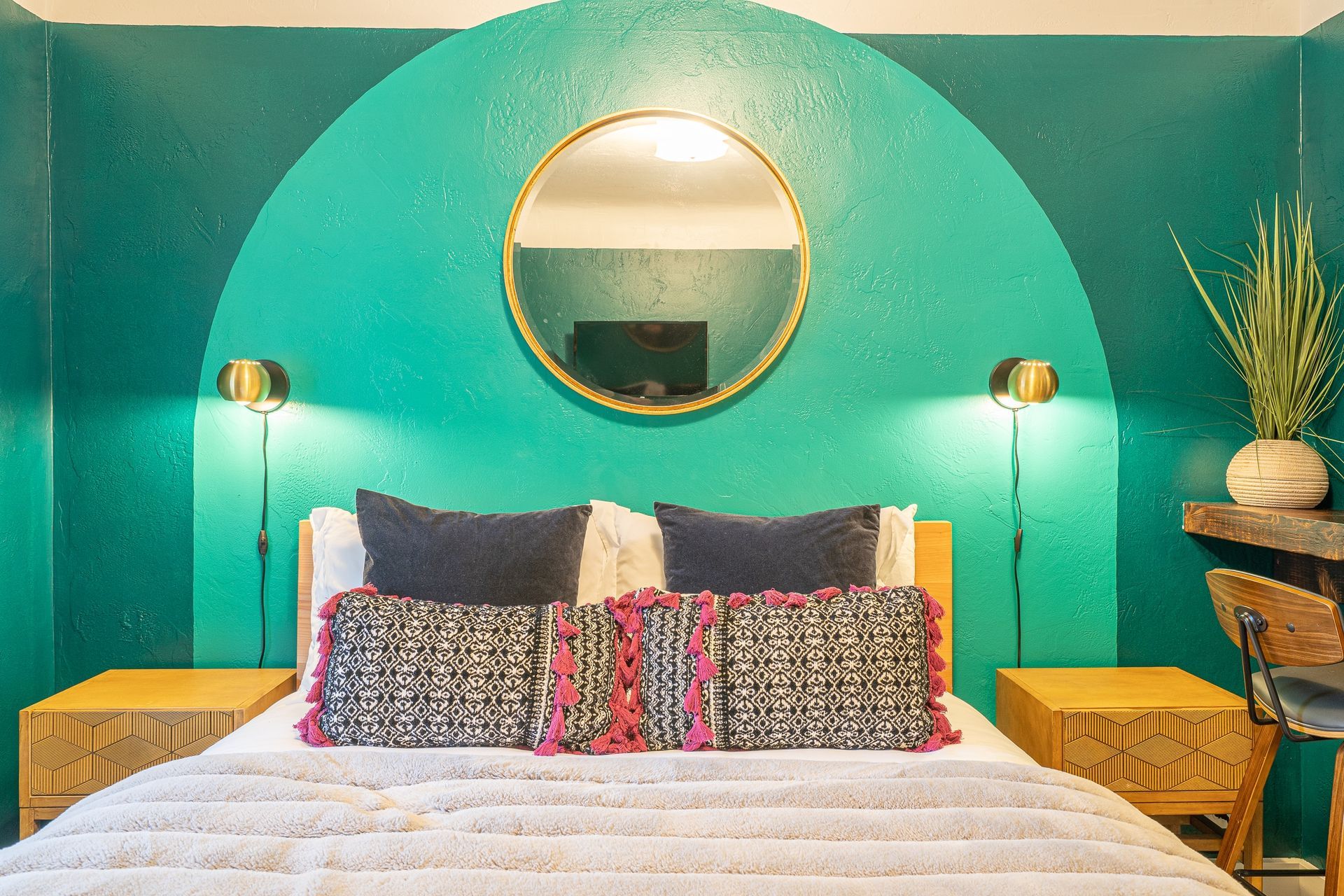 A bedroom with a bed , nightstands , and a mirror on the wall.