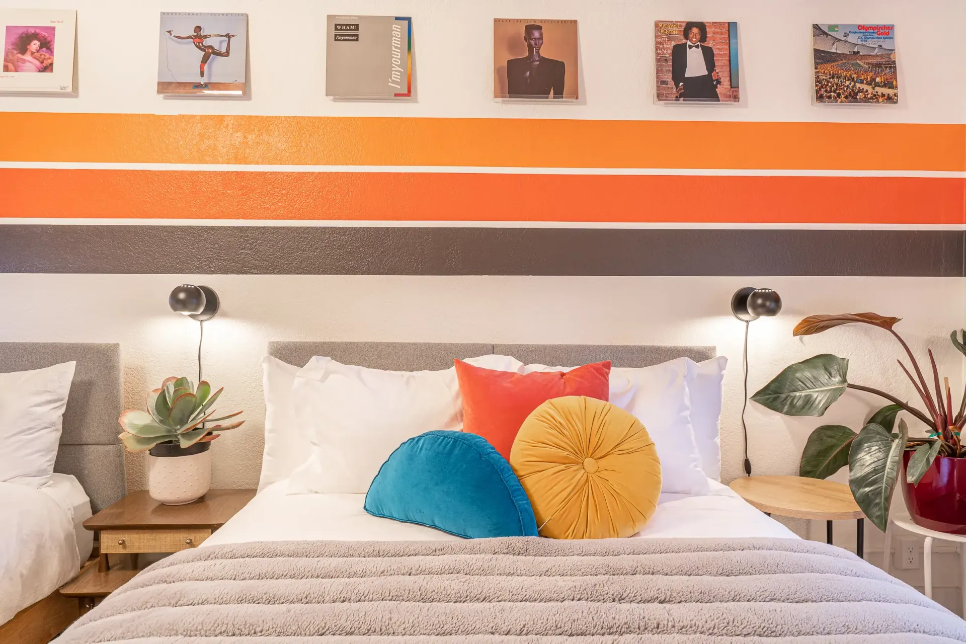 A bedroom with a bed , two nightstands , and a striped wall.