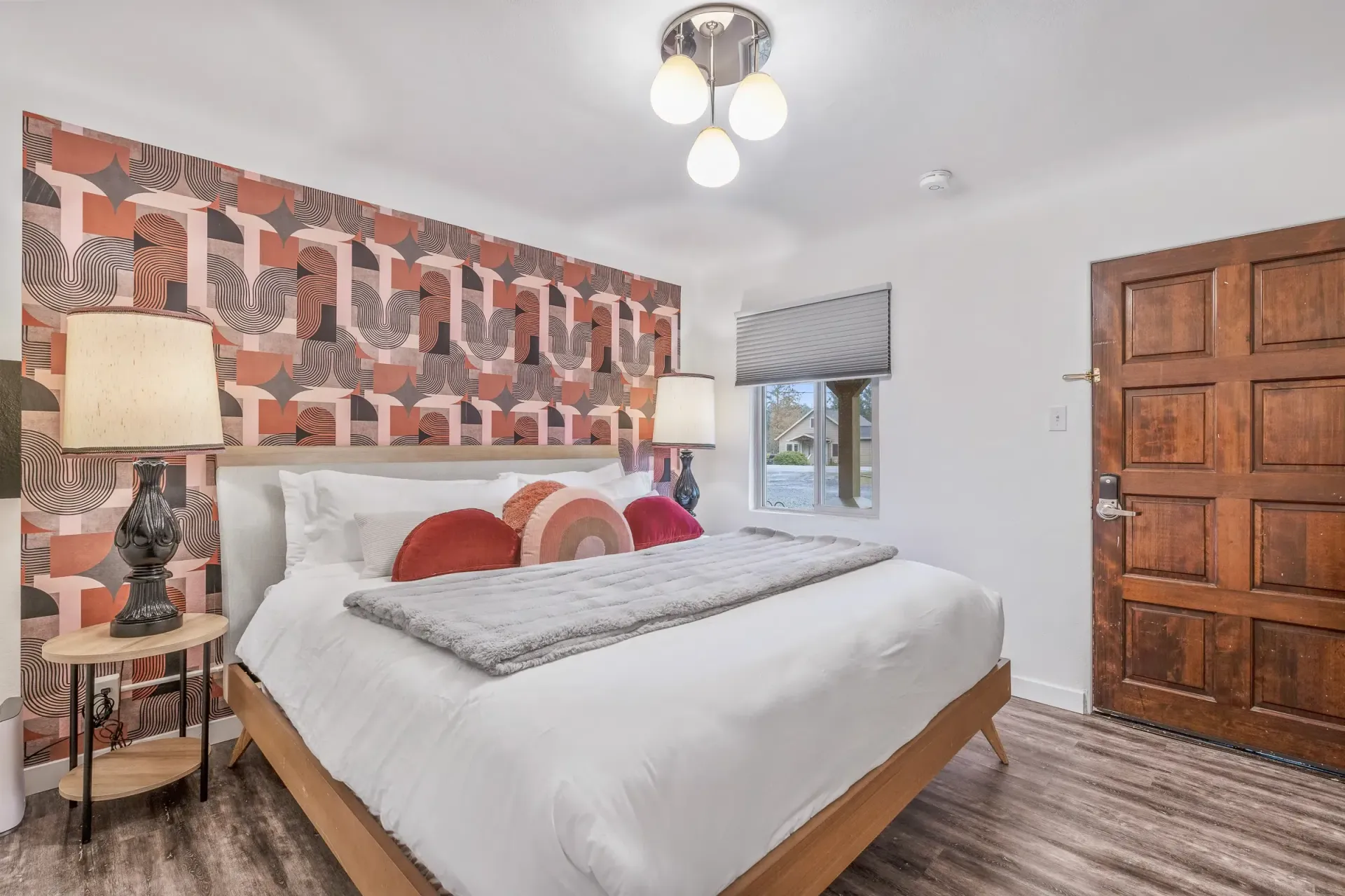 A bedroom with a bed , lamps , and a door.