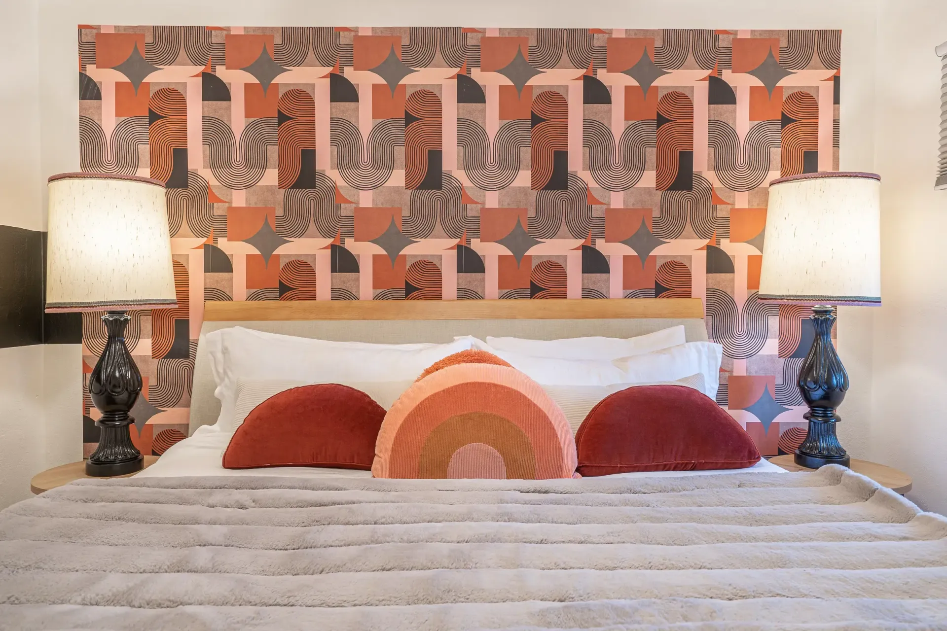 A bed with a patterned headboard and two lamps in a bedroom.