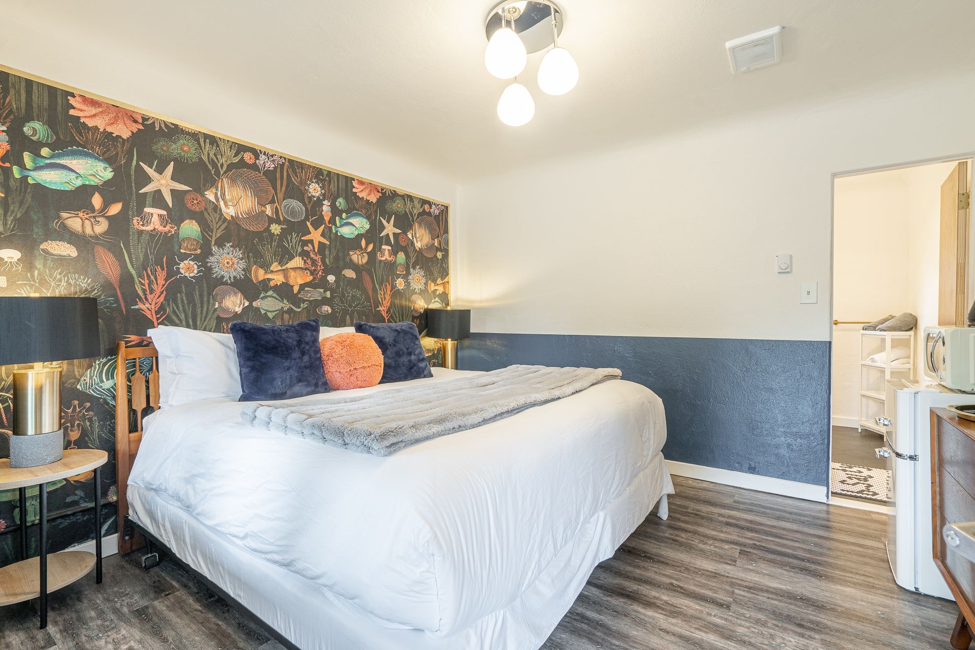A bedroom with a king size bed and a fish wallpaper on the wall.