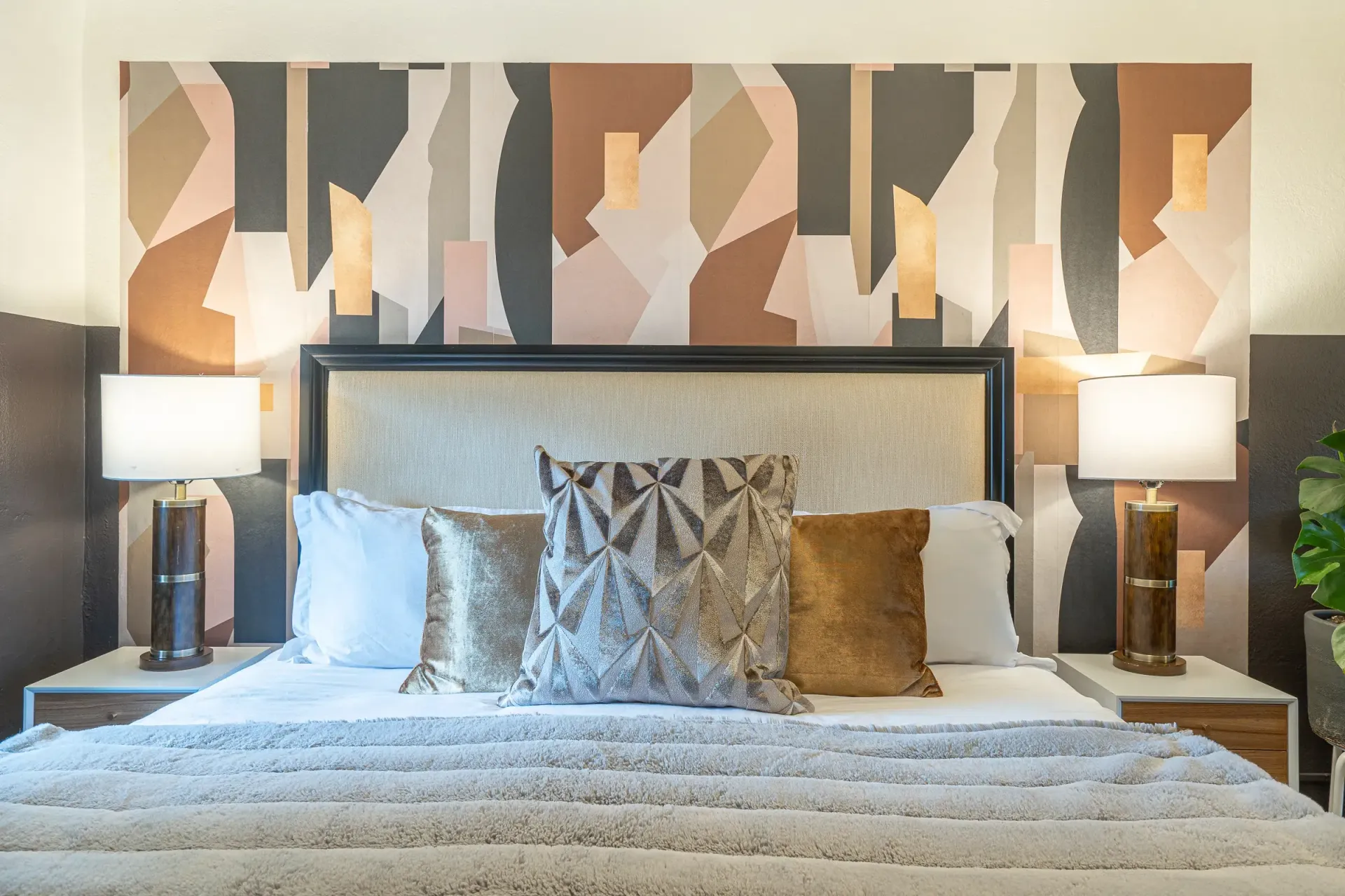 A bedroom with a bed , lamps and a painting on the wall.