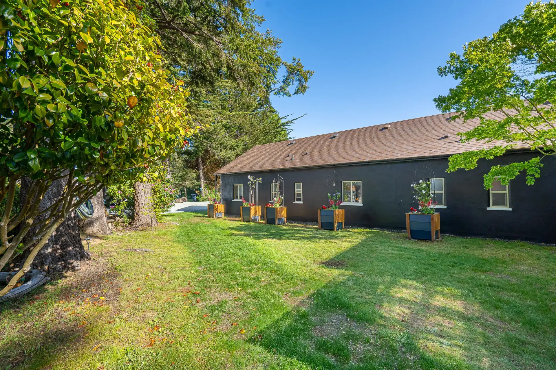 A black house with a brown roof is sitting on top of a lush green lawn.