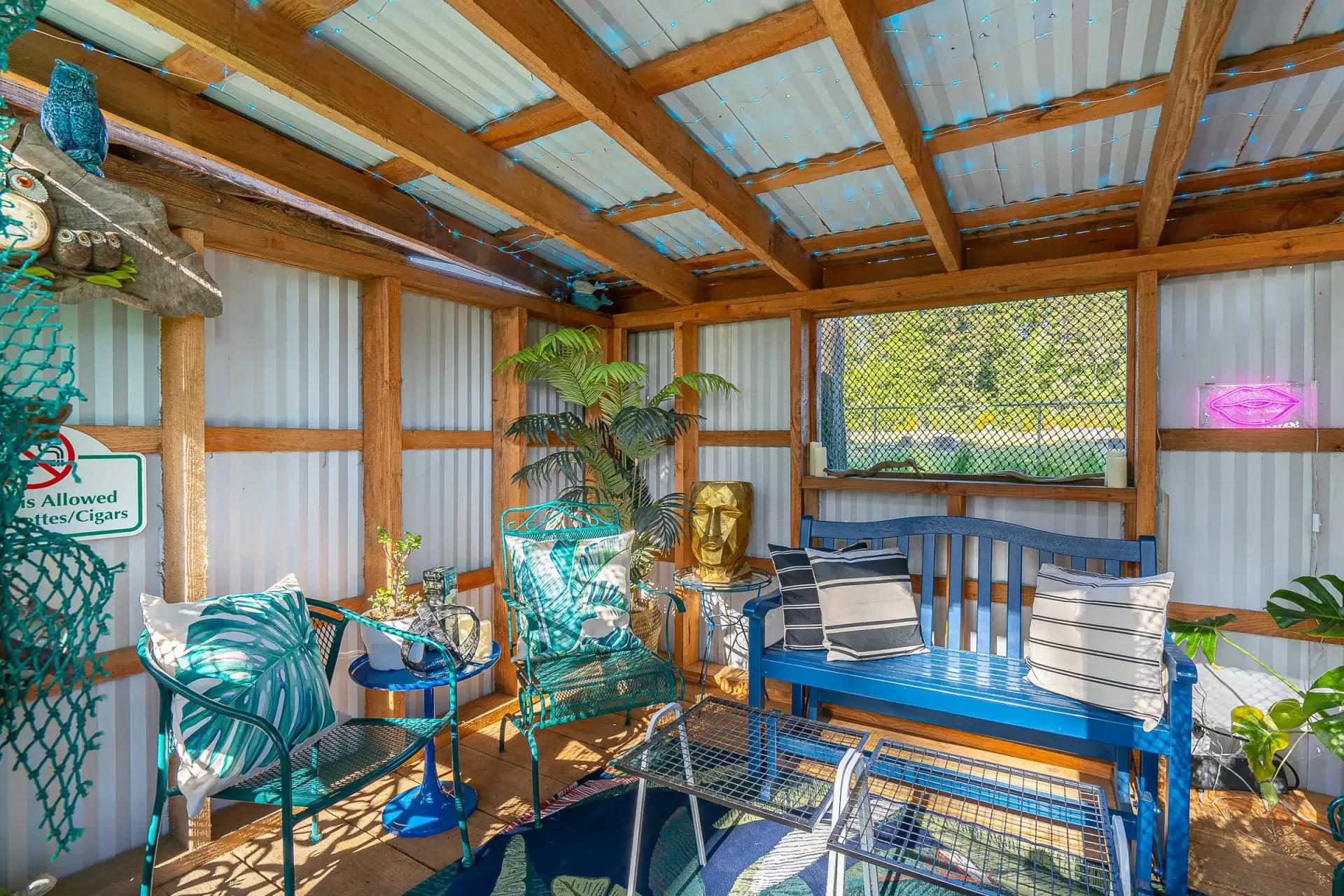 A covered patio with a bench , chairs , and a table.
