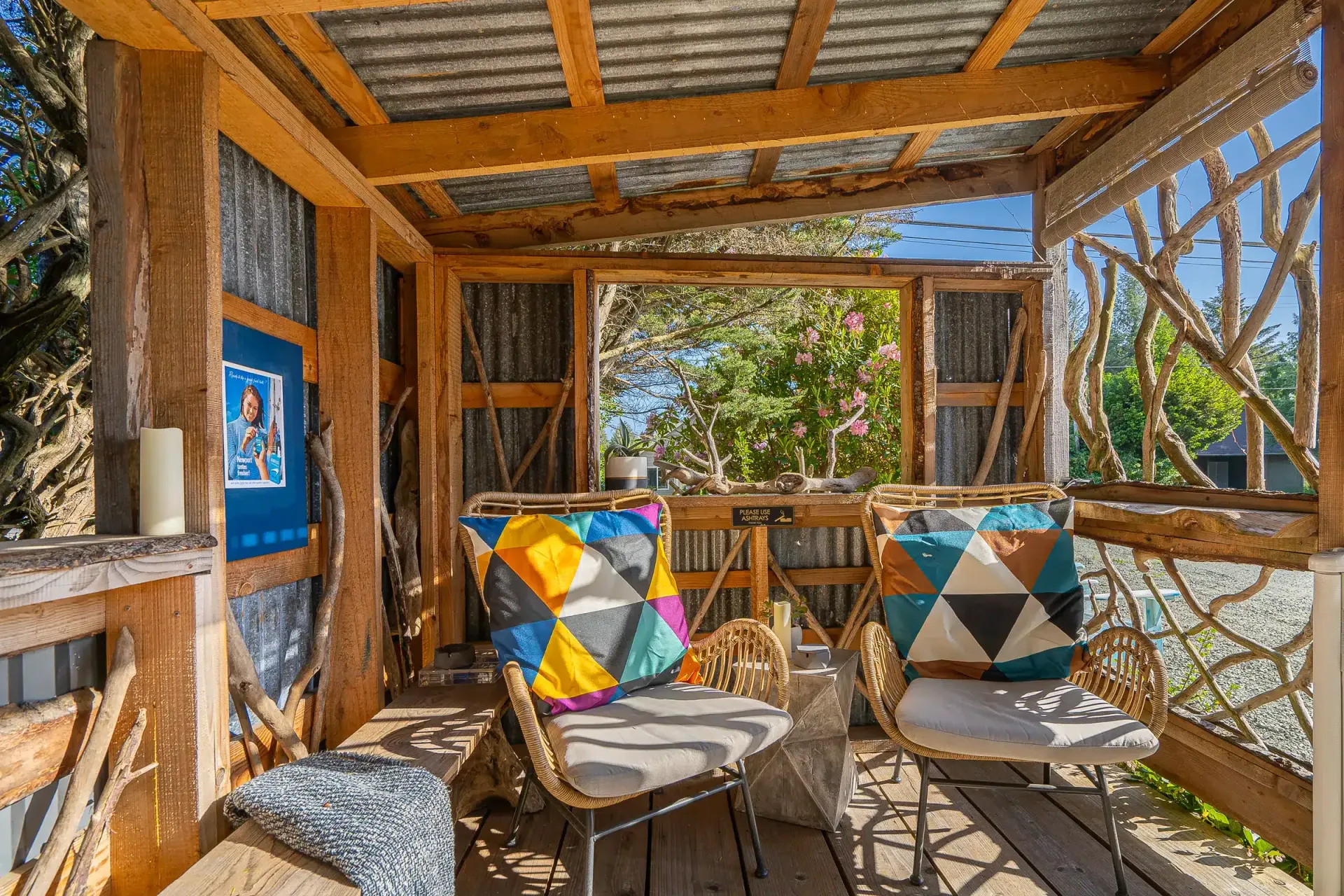 A wooden porch with a couch and chairs under a roof.