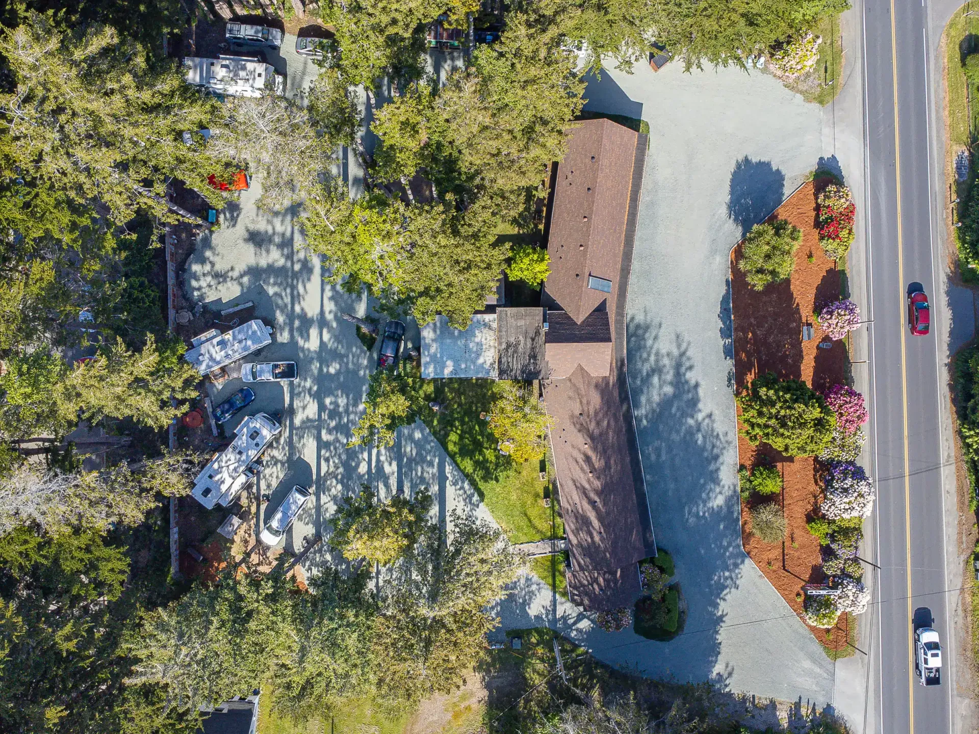 An aerial view of a house surrounded by trees and a road.