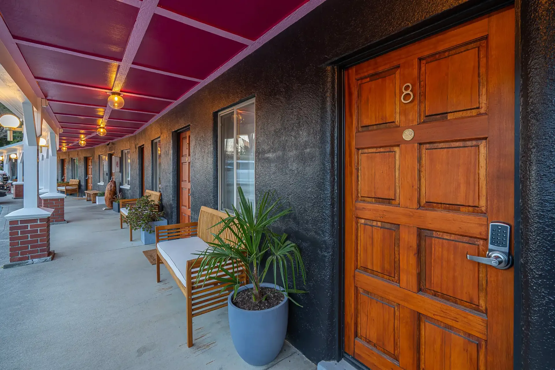 A hotel room with a wooden door and a bench in front of it.