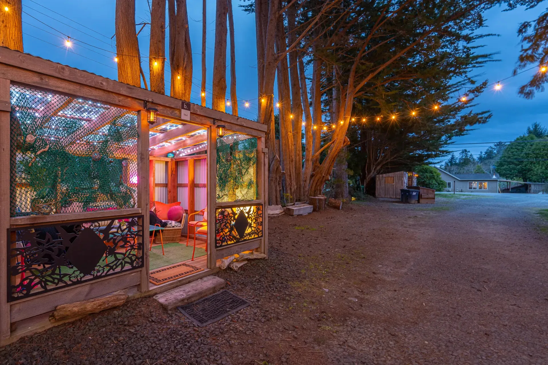A fence with lights hanging from it and trees in the background.