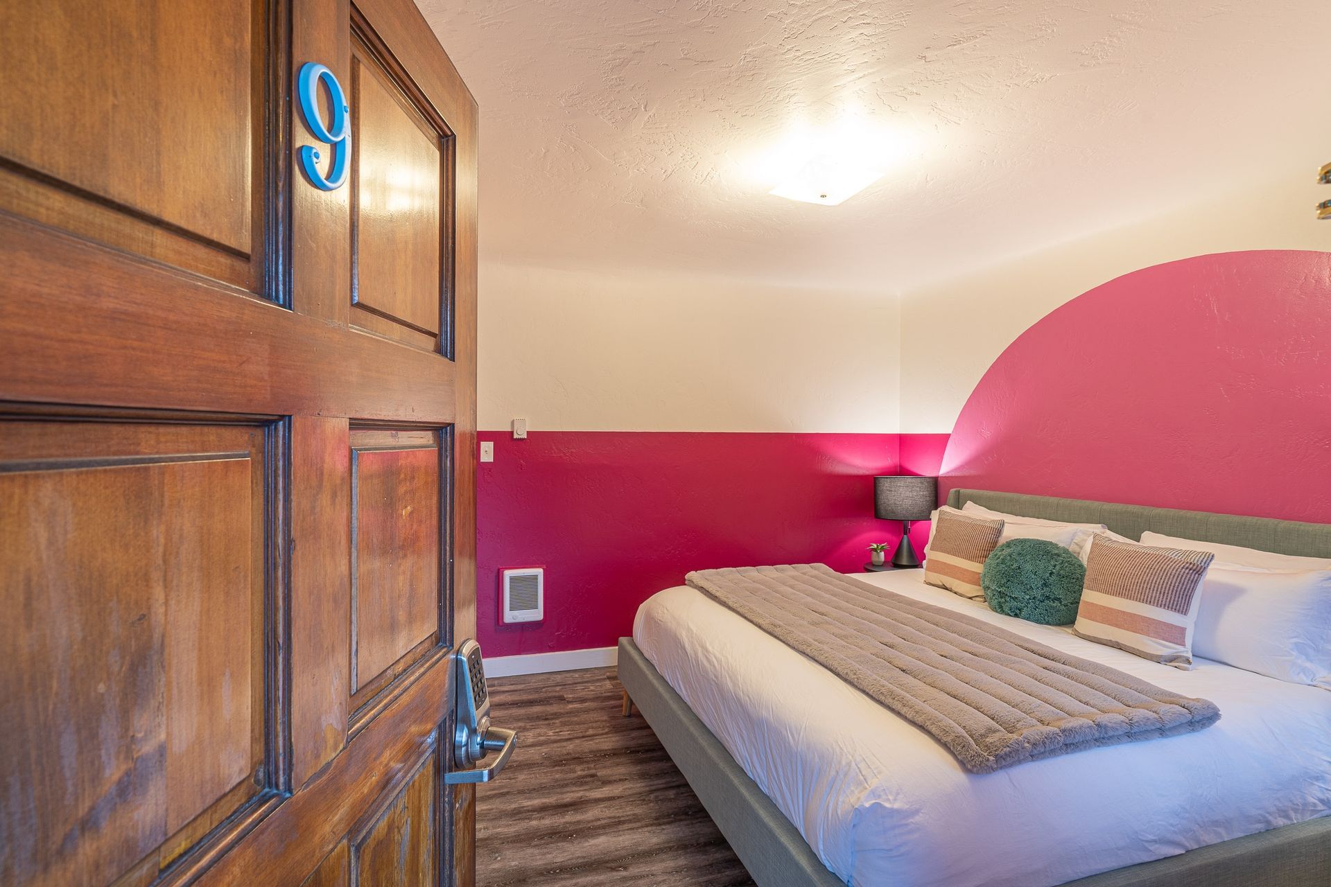 A bedroom with a king size bed and pink walls.
