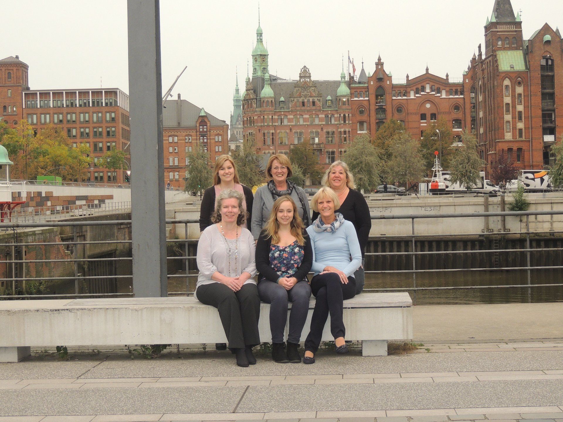 Eine Gruppe von Frauen posiert für ein Foto, während sie auf einer Bank sitzen