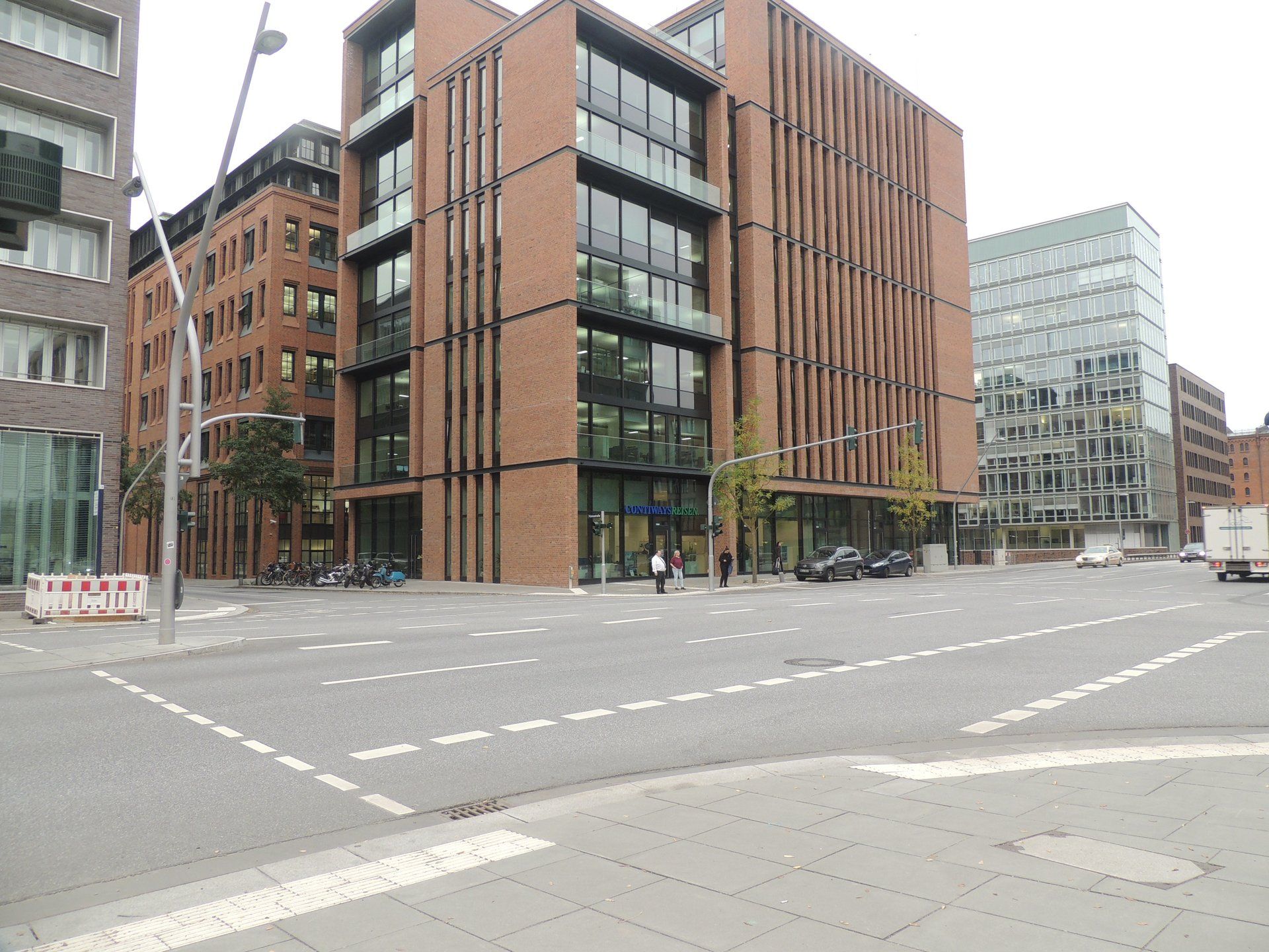 Eine belebte Kreuzung mit einem großen Backsteingebäude im Hintergrund