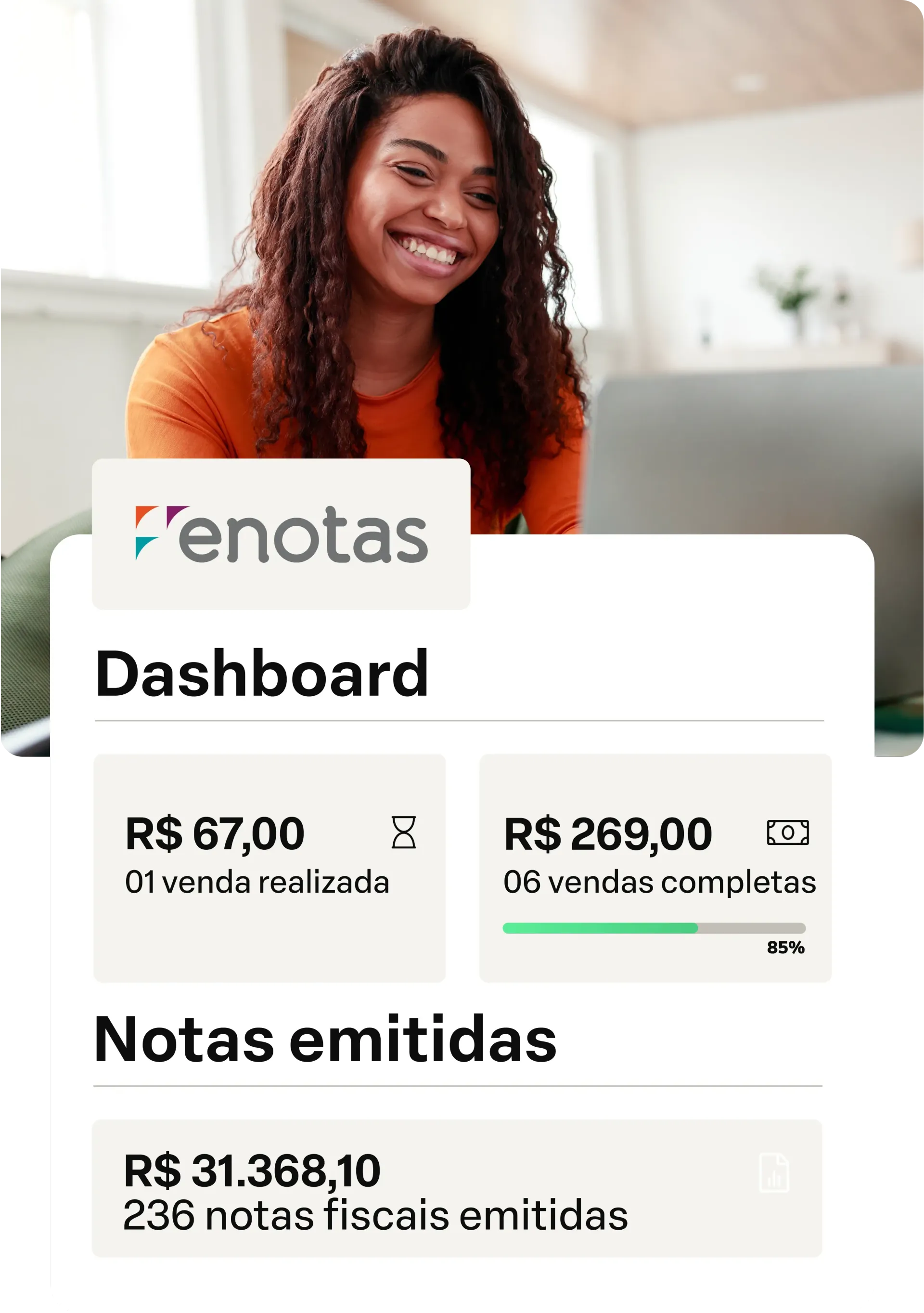 Uma mulher sorri sentada em frente a um laptop.