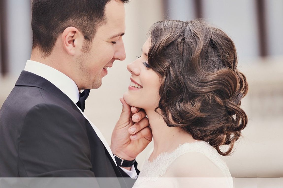 A bride and groom are looking into each other 's eyes.