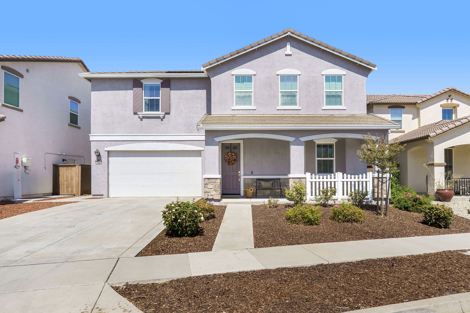 Two-story house with a light purple exterior, white trim, and a small front porch; sunny day.