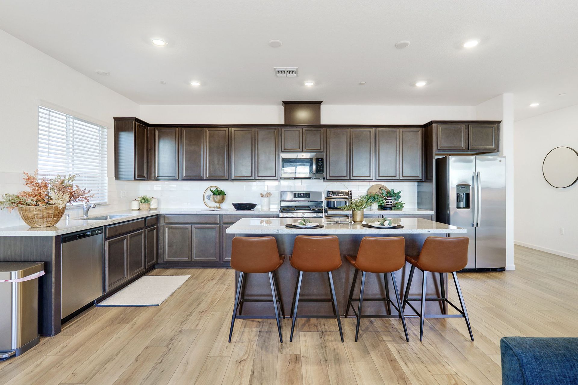 Modern kitchen with brown cabinets, stainless steel appliances, and island with bar stools.