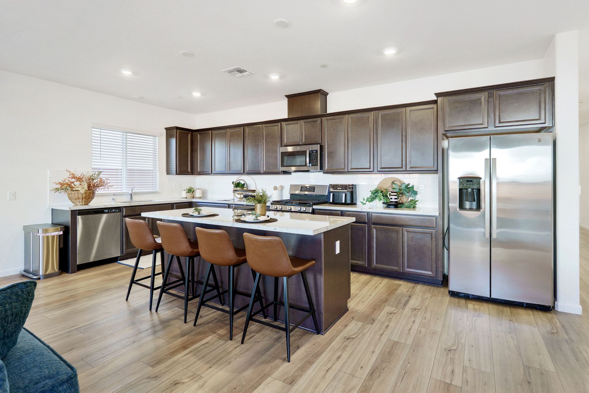 Modern kitchen with dark wood cabinets, stainless steel appliances, and island with bar stools.