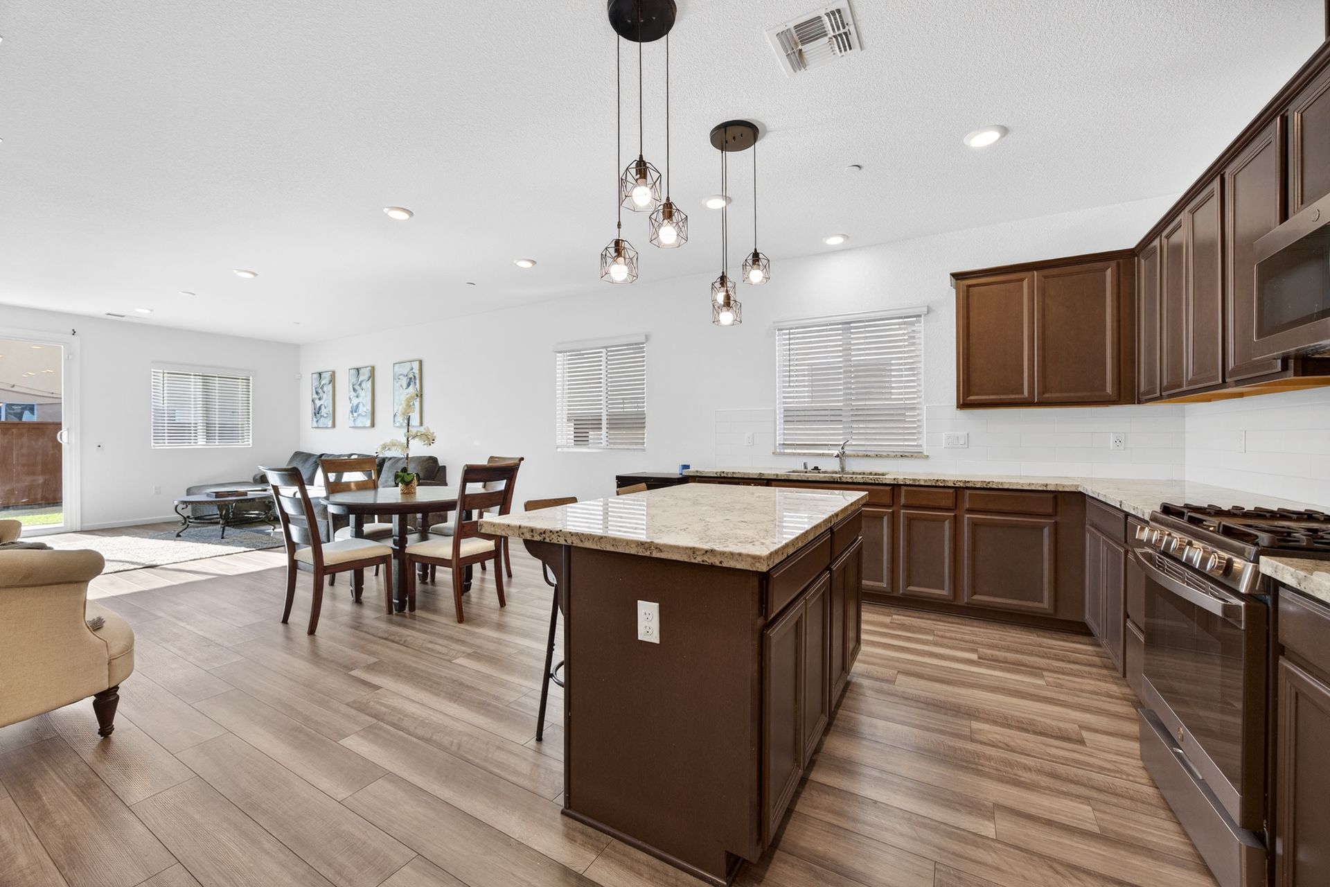 Modern kitchen with brown cabinets, island, and dining area with wood flooring.