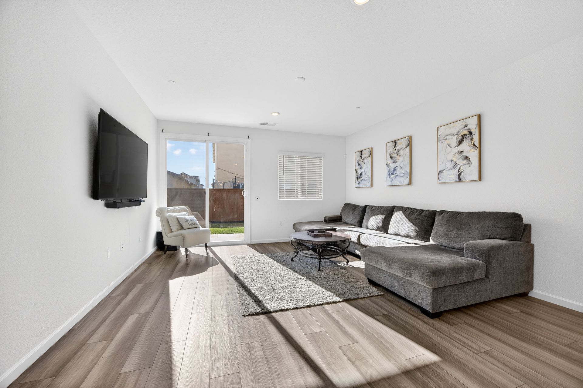 Modern living room with sectional sofa, TV, and outdoor access.