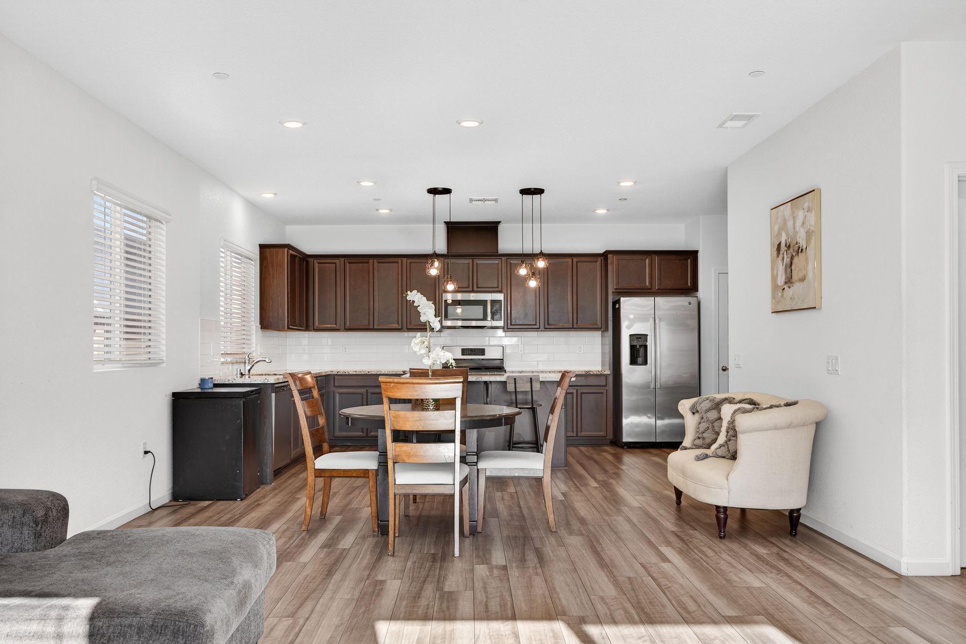 Open-plan kitchen and dining area with dark wood cabinets, stainless steel appliances, and wooden flooring.
