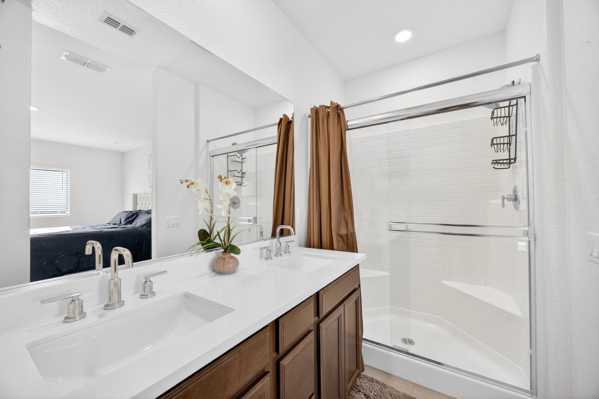 Bathroom with white countertop, brown cabinets, and glass shower.