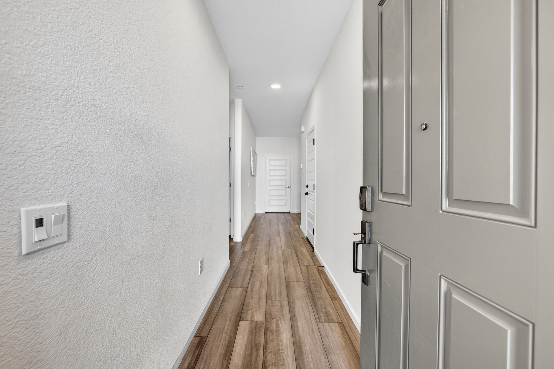 Entryway with wood-look floor, white walls, and a partially open white door.