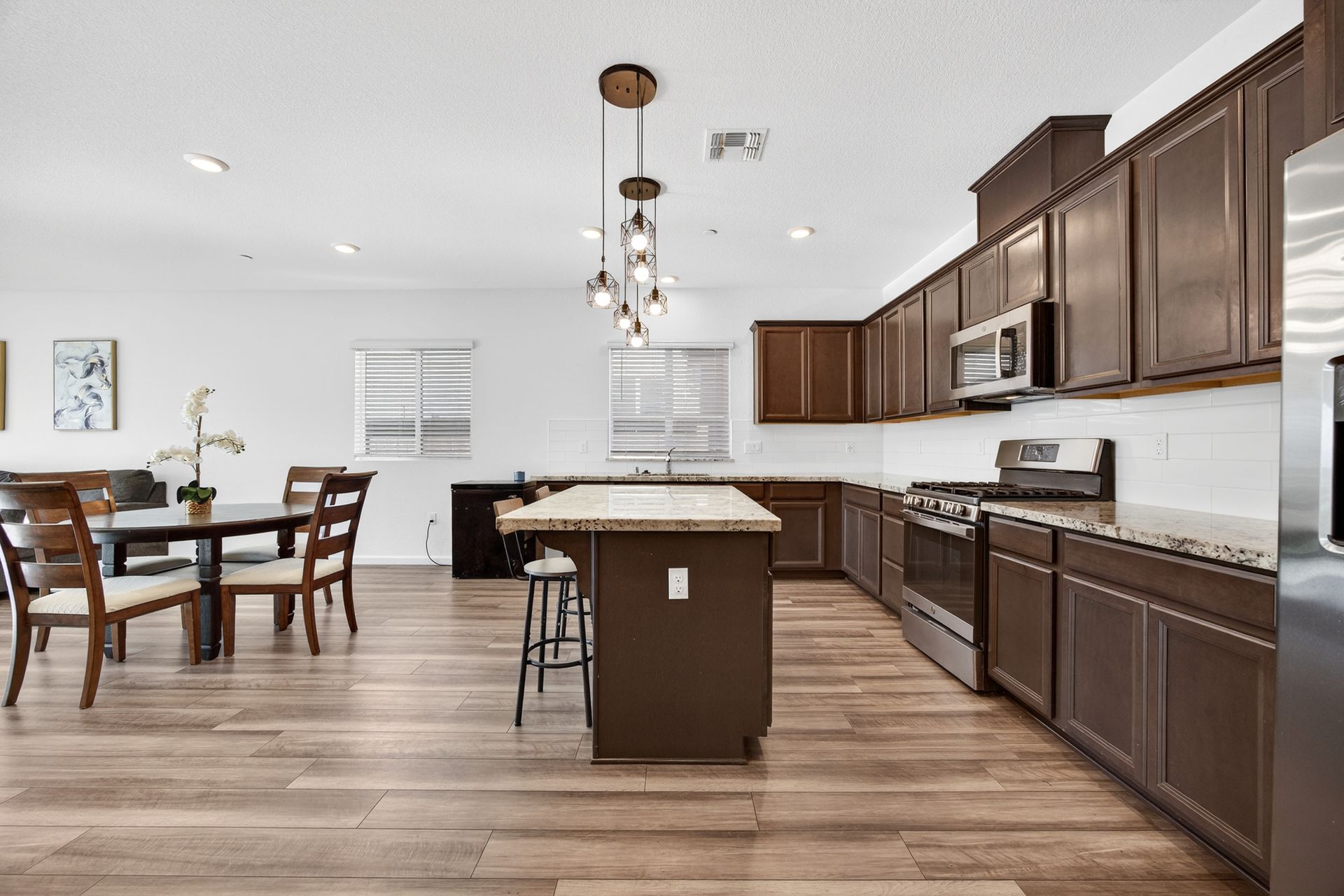 Modern kitchen with dark brown cabinets, granite countertops, and a dining area.