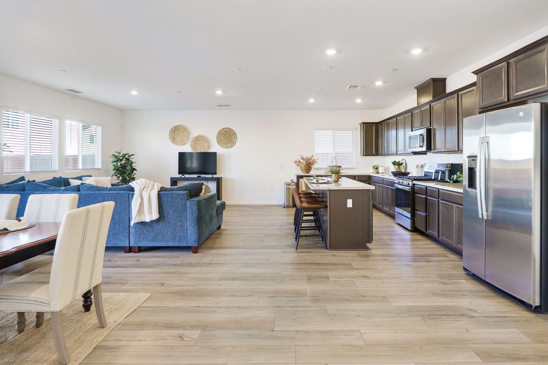 Spacious open-plan living area with blue sectional, kitchen island, and stainless steel appliances.