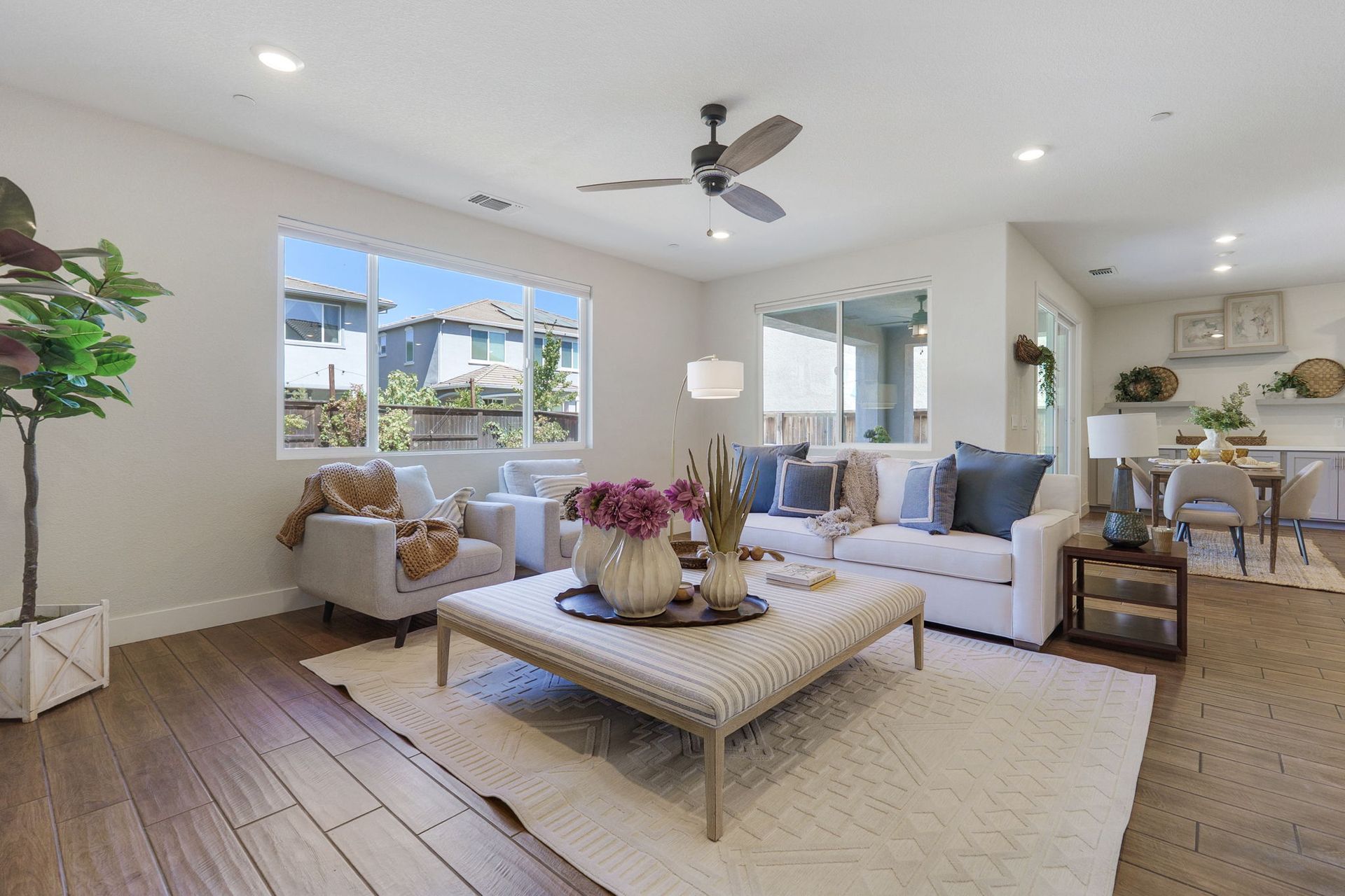 Living room with white sofa, rug, and coffee table, hardwood floors, and large windows.