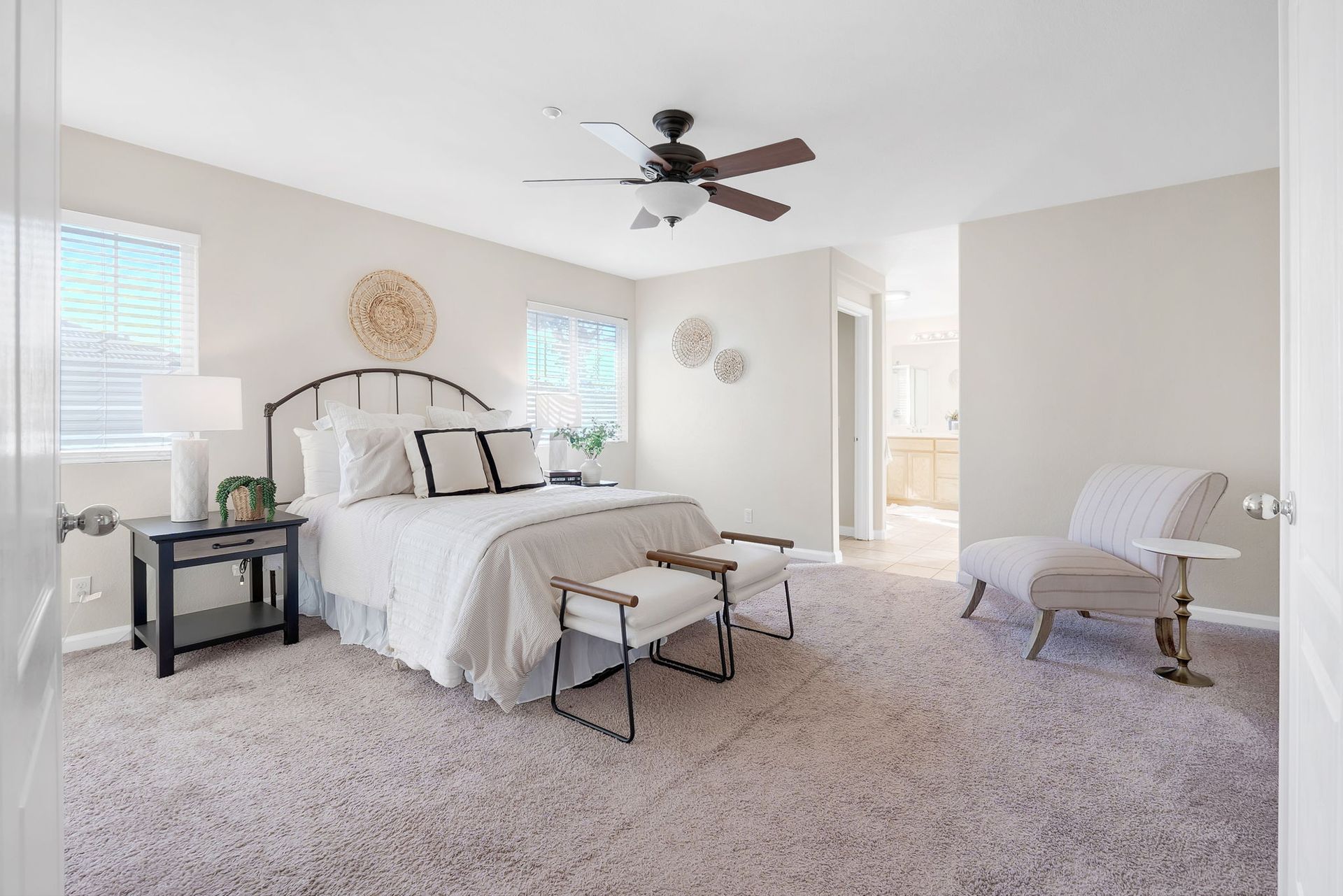 Bedroom with bed, bench, armchair, and ceiling fan; neutral tones.