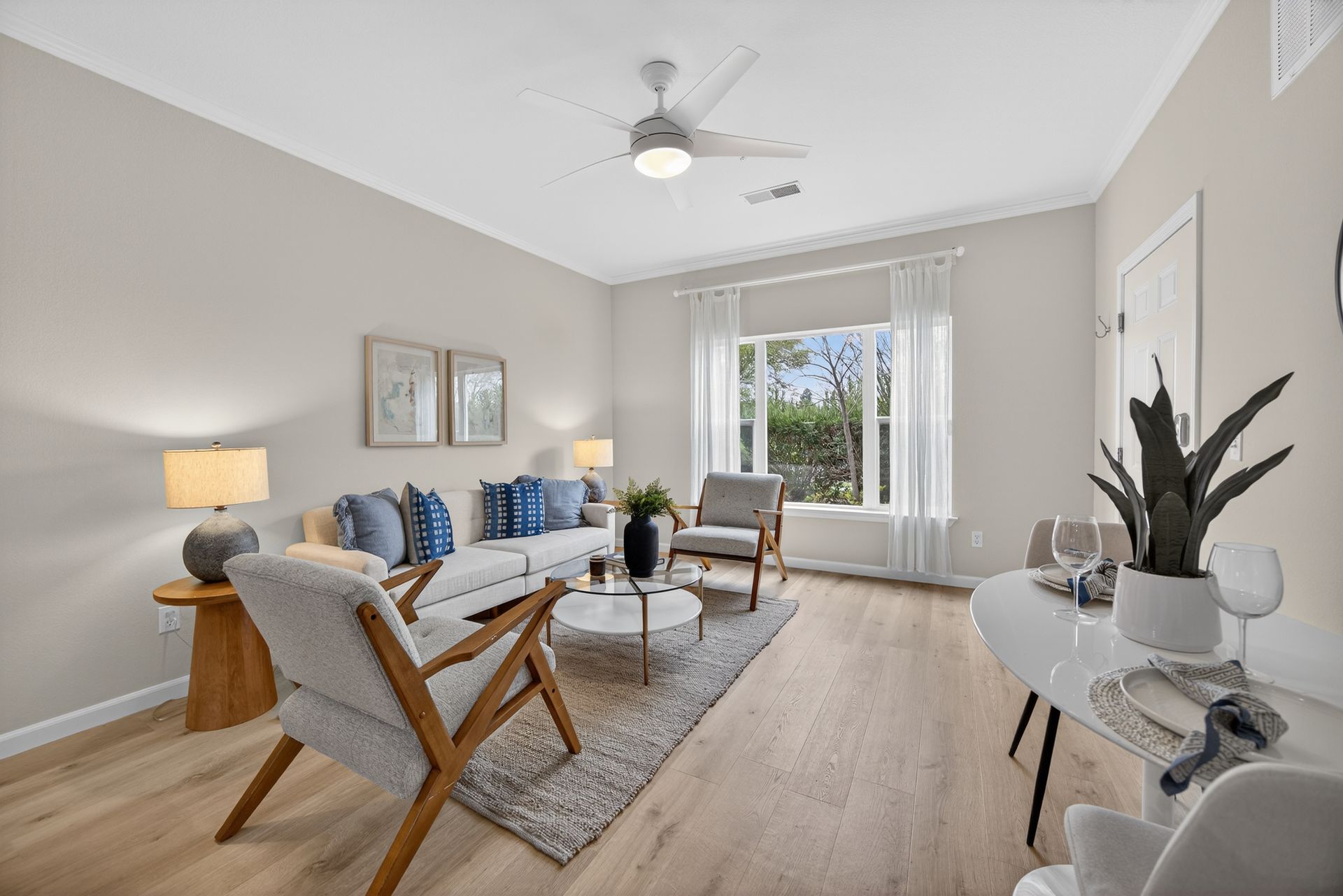 Bright living room with white walls, wood floors, furniture, and a window.