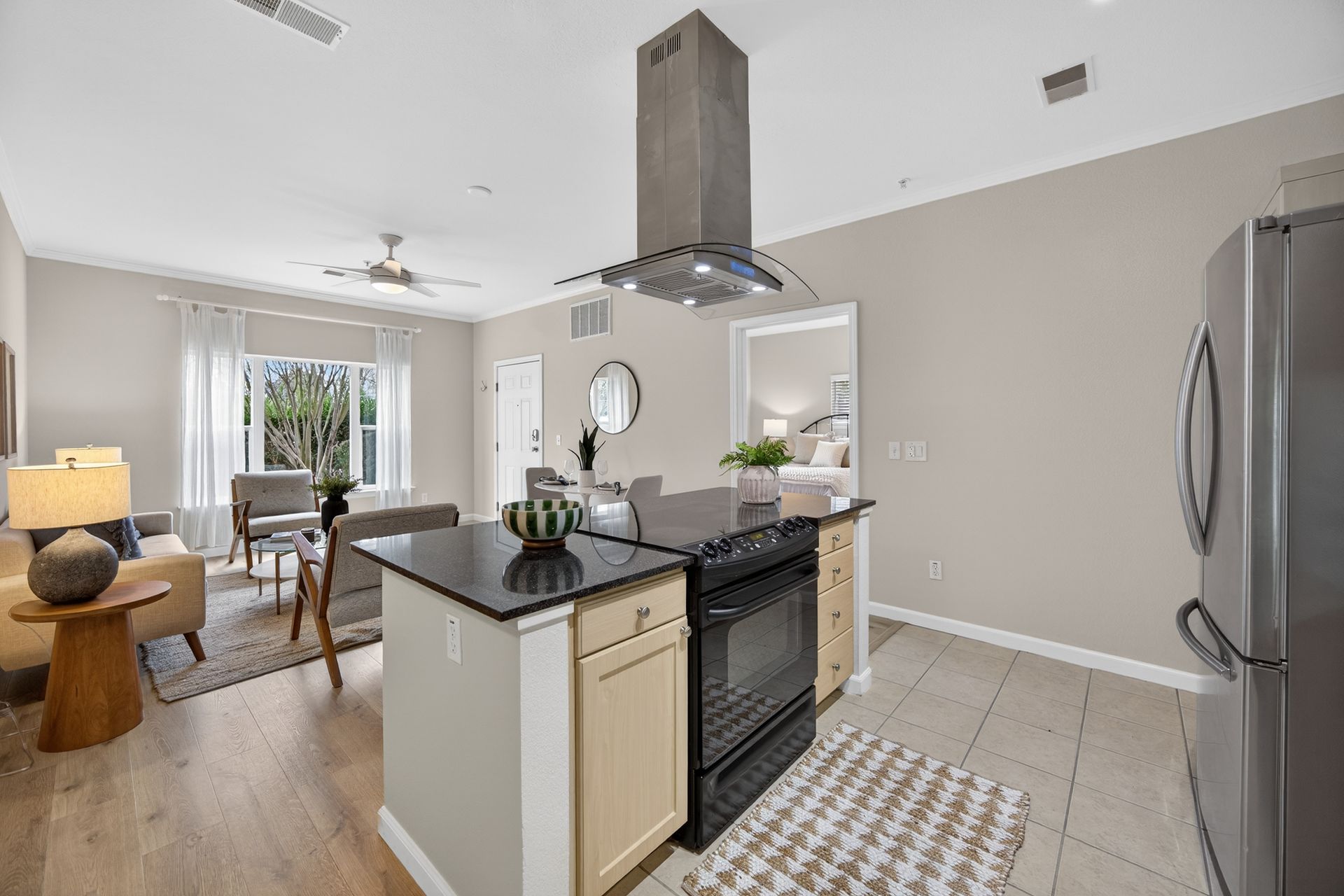 Open-concept kitchen/living area with an island, stainless steel appliances, and a window with natural light.