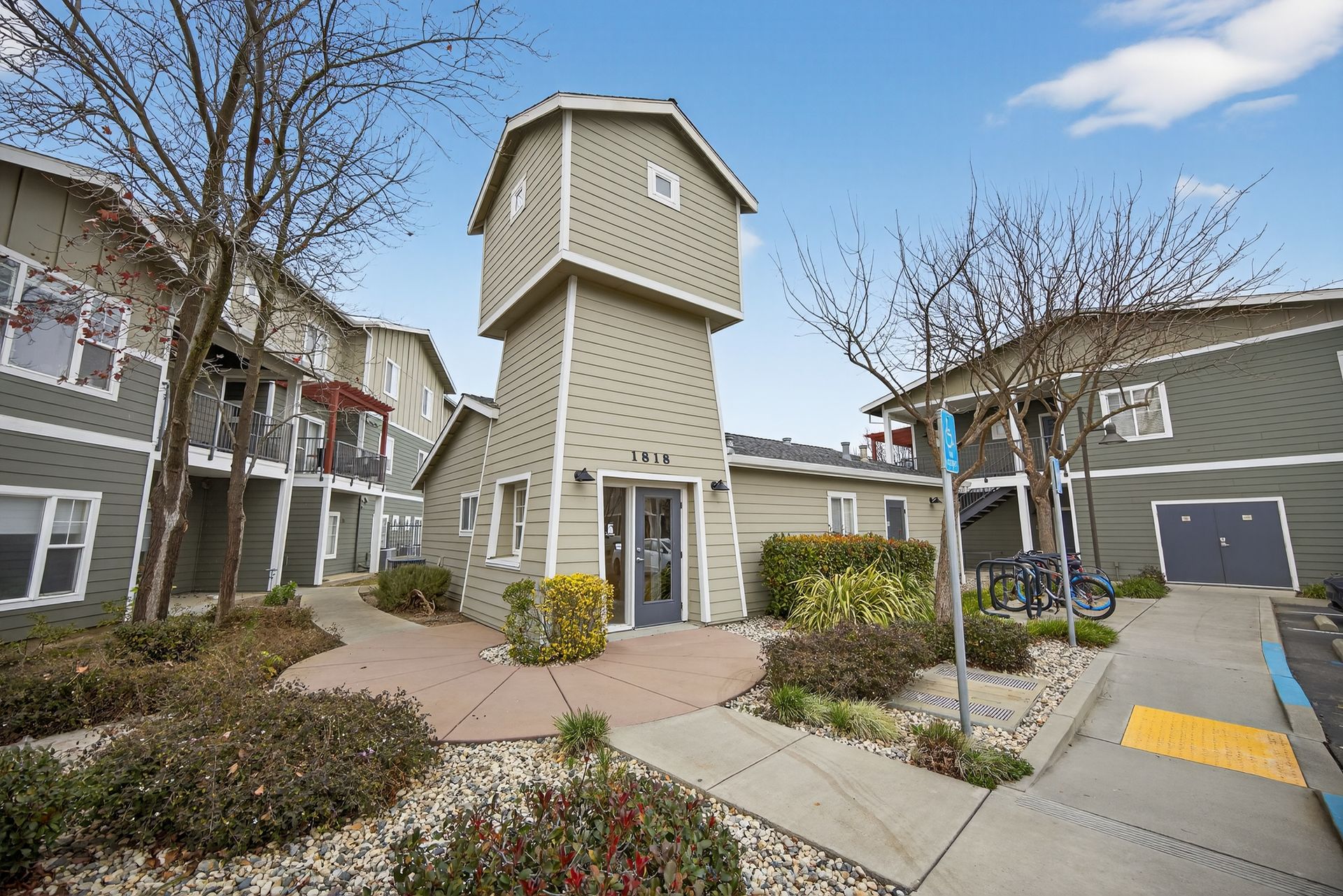 Apartment complex exterior with a light-colored, tower-like office building and other multi-unit buildings.