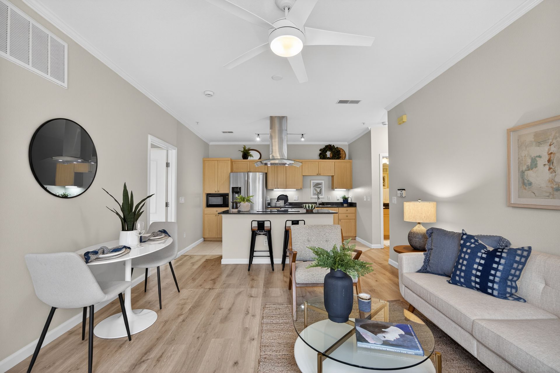 Bright living space with open kitchen, dining area, and living room; light wood floors, beige walls, and modern decor.