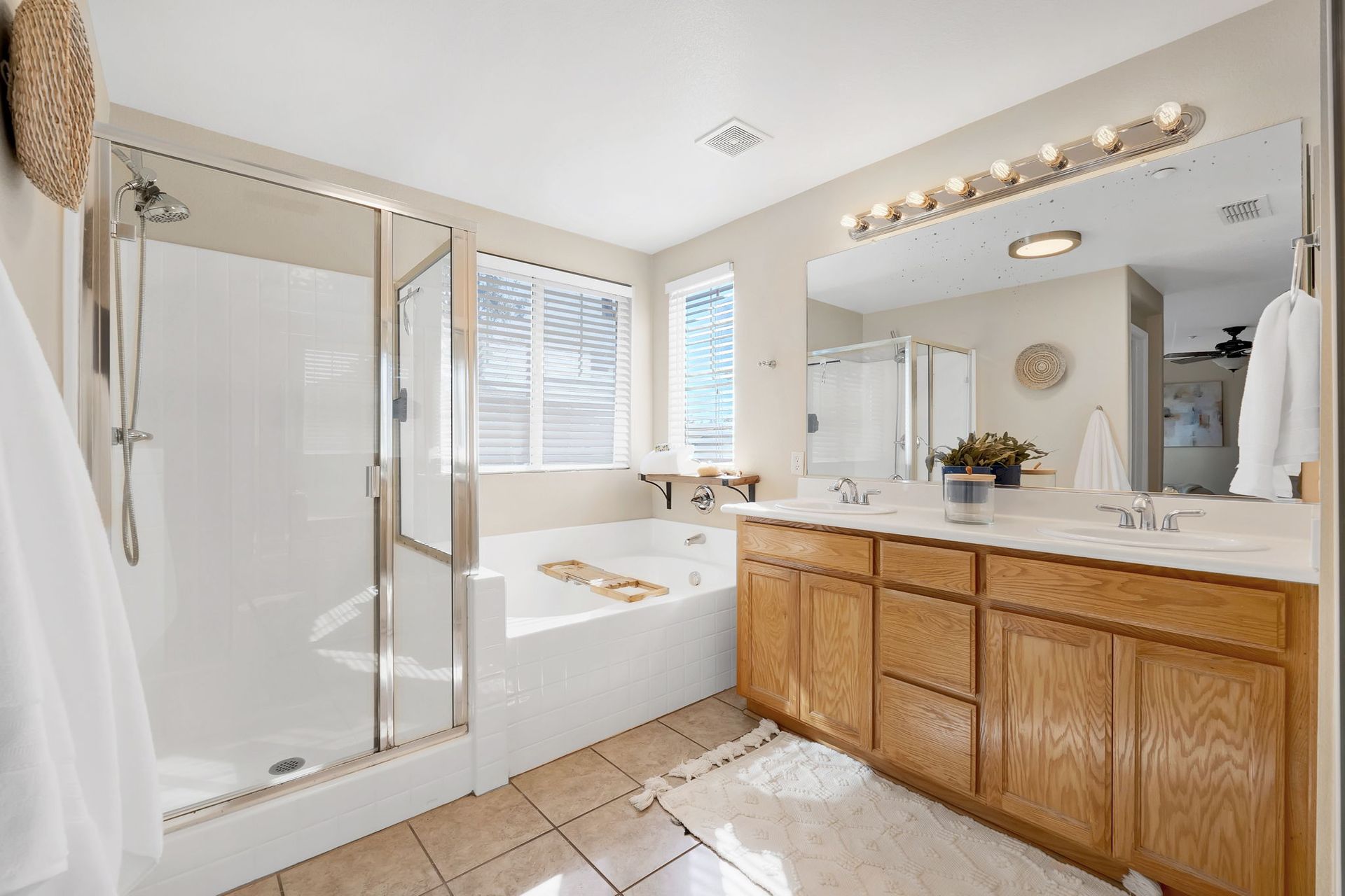 Bathroom with shower, bathtub, vanity with double sinks, and beige tile.