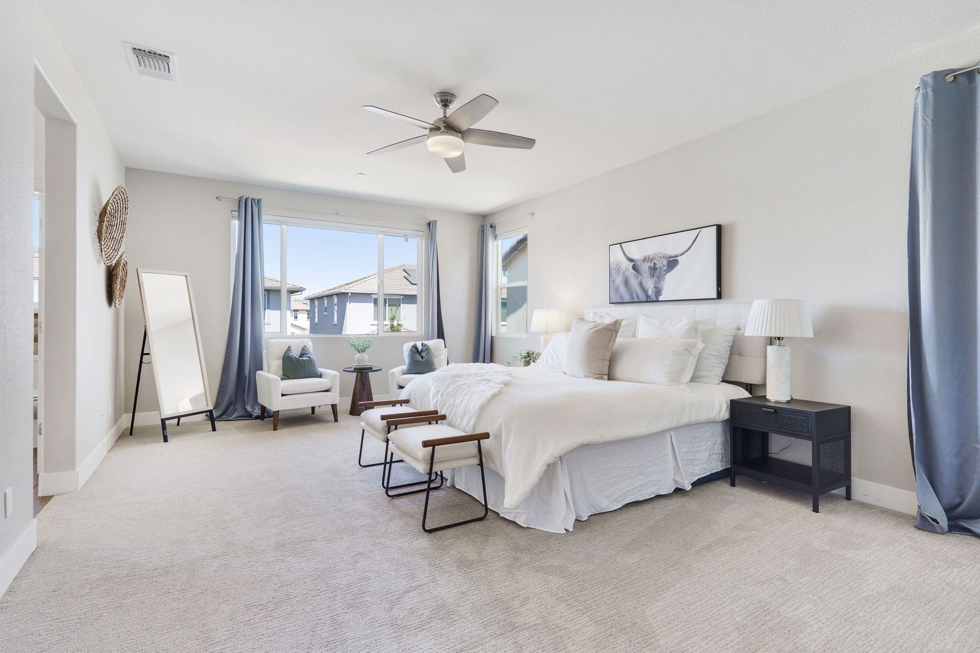 Bedroom with a large bed, seating area, and blue curtains.