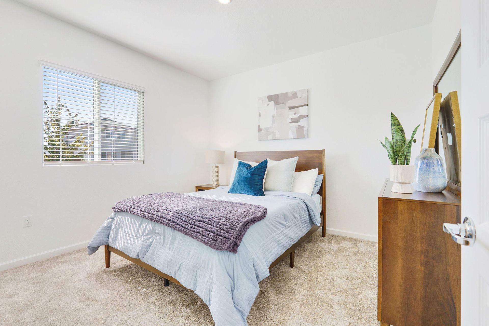 Bedroom with bed, dresser, window, and neutral carpet.
