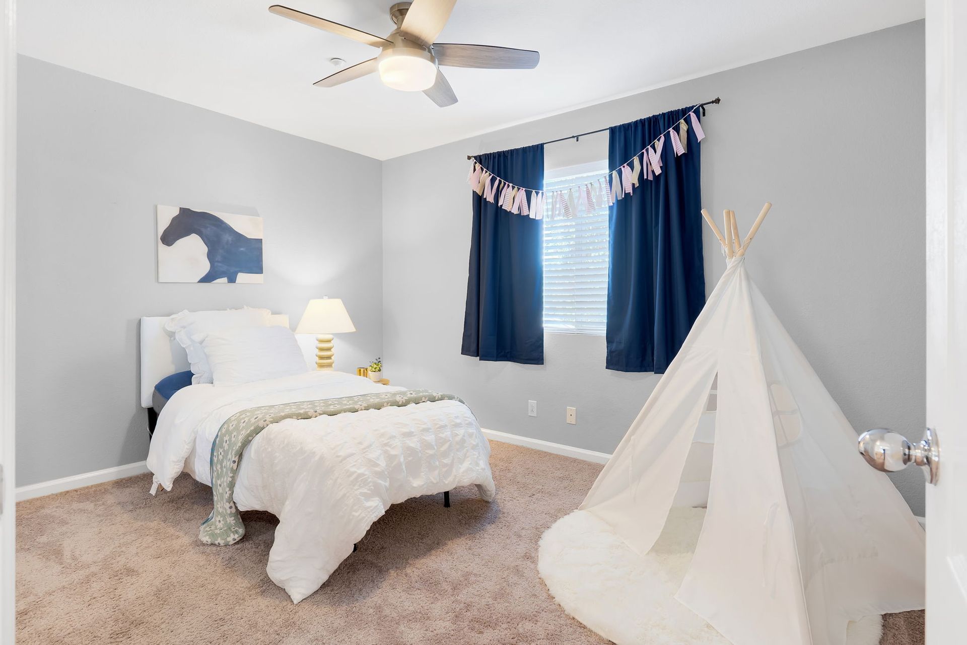 Bedroom with a white bed, blue accents, a teepee, and a horse painting on a blue wall.
