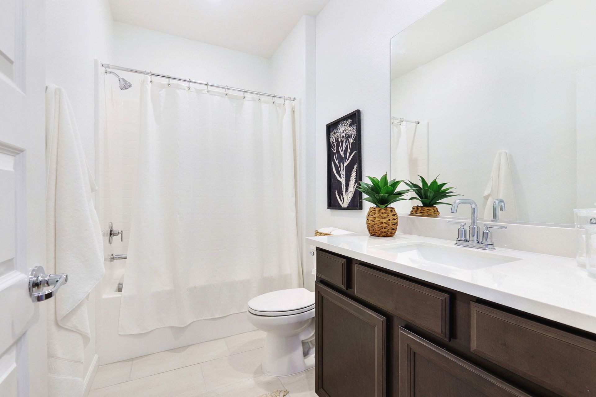 Bathroom with a white bathtub, toilet, and vanity with a dark brown cabinet.